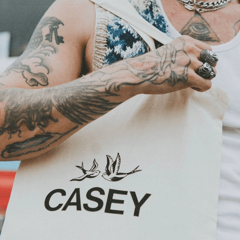 Moving image showing artwork for Casey - Puncture Wounds to Heaven, alongside branded Casey merchandise printed on a tote bag.